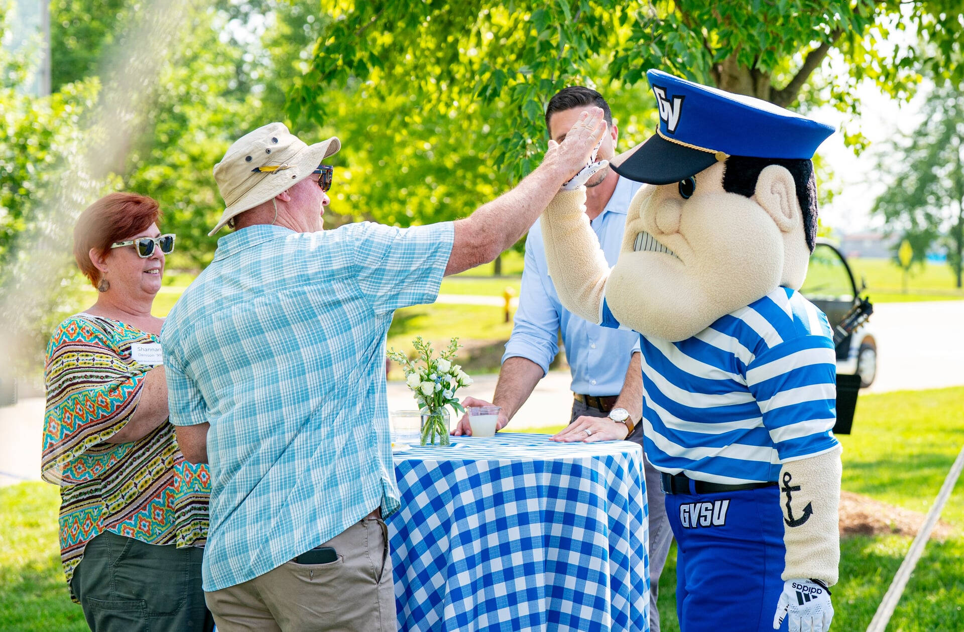 Man at outdoor event high-hiving Louie the Mascot